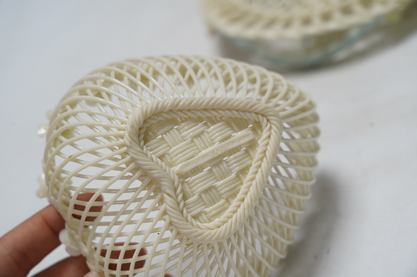 Three 20th century Belleek items with applied floral decorations; a jug, 15cm high, and two basket work dishes, largest 20cm wide. Condition - good